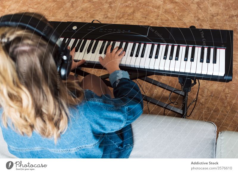 Junge Frau spielt zu Hause elektronisches Klavier spielen heimwärts Musik jung Instrument gemütlich Musiker elektrisch Sofa Komponist Feuerstelle Synthesizer