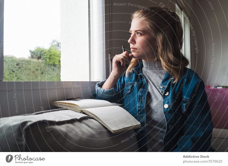 Nachdenkliche Frau mit Notebook am Fenster sitzend Tagebuch heimwärts besinnlich jung Schüler Notizblock nachdenklich lesen lässig Denken Windstille ruhig