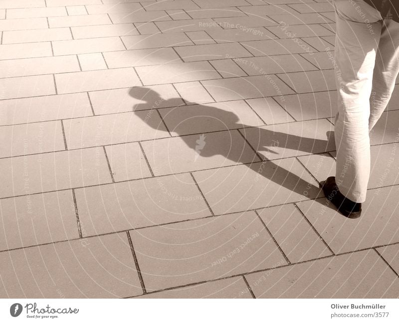 Schattenmann Mann Bürgersteig gehen Beine laufen Bodenbelag Pflastersteine