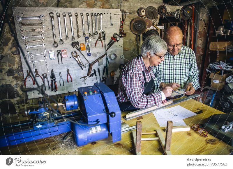 Seniorenpaar in einer Tischlerei Schreinerei Paar arbeiten Zimmerer Blick plant Werkstatt Holz reif Maschine Business Kaukasier heimwärts Ruhestand Arbeiter
