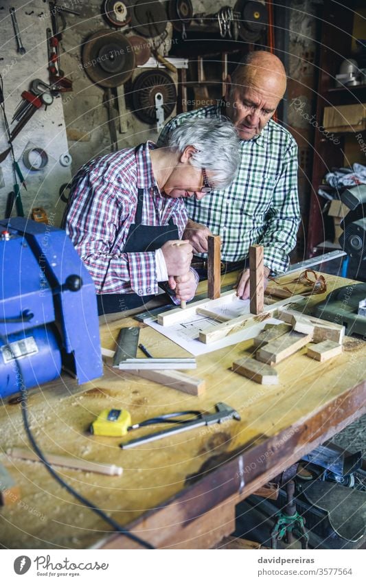 Seniorenpaar in einer Tischlerei Hobelbank Zimmerer Frau Zusammenbau Stuhlbein diy einstecken handgefertigt Paar kollaborierend Schreinerei Möbel Werkstatt