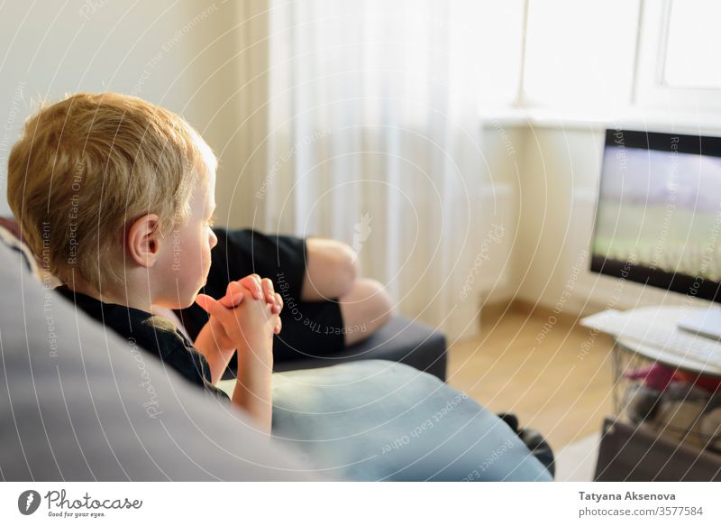 Kleiner Junge sieht zu Hause einen Film auf dem Fernsehbildschirm FERNSEHER heimwärts Menschen zuschauend Fernsehen Kind Sofa Liege Sitzen Familie Bildschirm