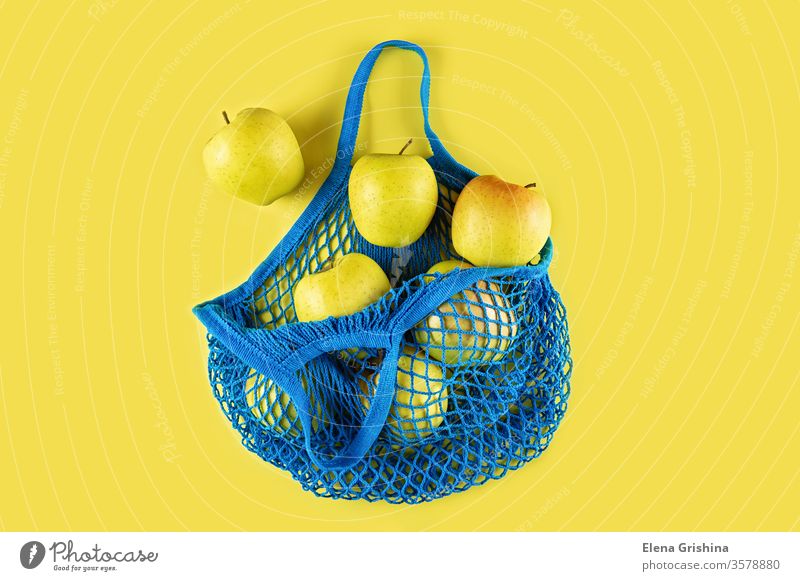 Reife Äpfel in einer blauen Schnurtüte auf gelbem Grund. keine Verschwendung Öko-Tasche Netzbeutel Apfel Baumwolle Einkaufsnetz Ökologie Konzept ökologisch