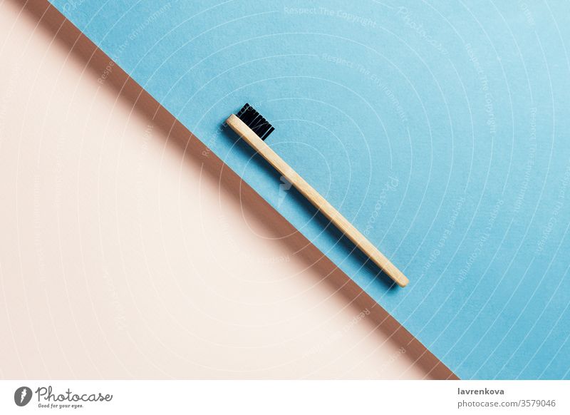Umweltfreundliche, nachhaltige Zahnbürste aus Bambuskohle auf blauem und pfirsichfarbenem Hintergrund, selektiver Fokus minimalistisch flache Verlegung Bad