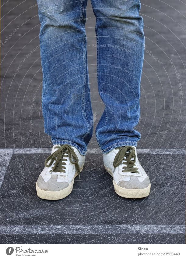 Jeans und Turnschuhe Beine Männerbeine Fuß Füße Schuhe Sneakers Dresscode leger casual smart stehen Straße Asphalt Mensch Außenaufnahme mehrfarbig