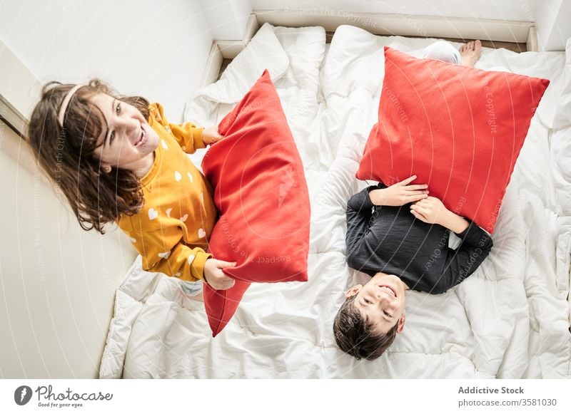 Verspielte Geschwister mit Kissenschlacht im Bett Geschwisterkind Kopfkissen kämpfen heimwärts Spaß Kinder Decke spielerisch spielen Bruder räkeln Schwester