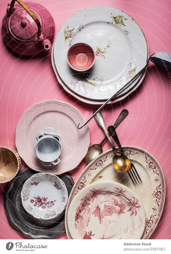Satz bunter Keramikplatten und Glaswaren auf lebhaft rosa Oberfläche Teller Utensil Geschirr Besteck altehrwürdig Kulisse Küchengeräte Sammlung verschiedene