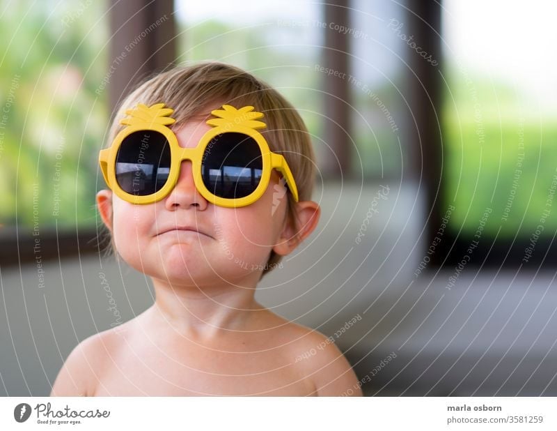 Kleiner Junge trägt eine Sonnenbrille mit gelber Ananas auf der hinteren Veranda Kleinkind mit Sonnenbrille Glück sonnig heimwärts Haus hintere Veranda