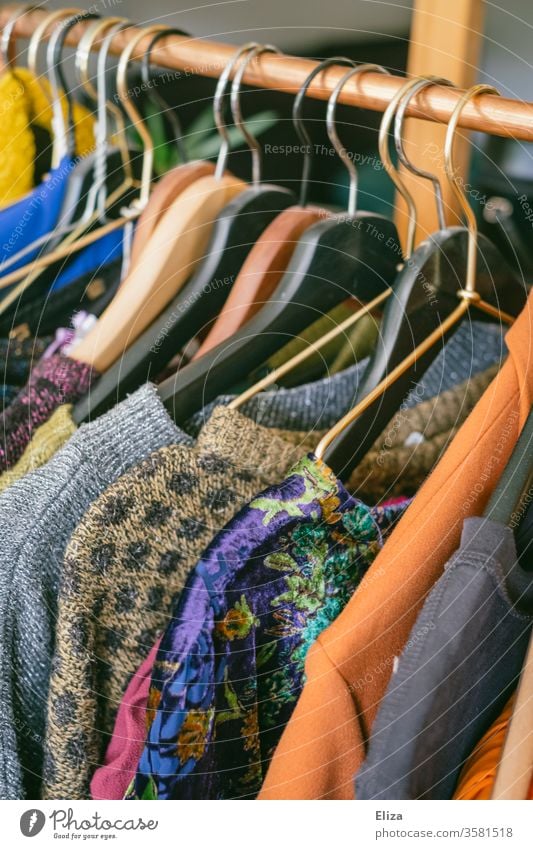 Kleidung auf einer Kleiderstange im Second Hand Geschäft oder auf dem Flohmarkt Second-Hand Laden gebraucht vintage Mode Bekleidung günstig slow fashion bunt