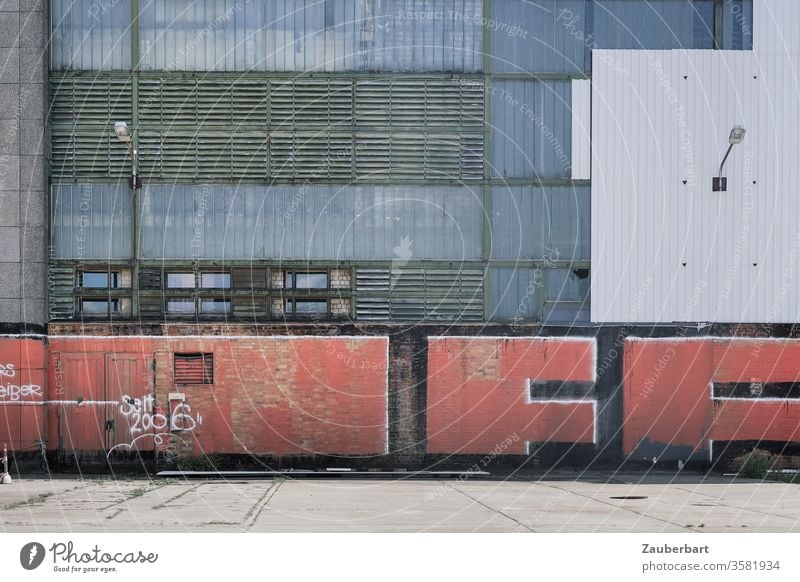 Fassade einer Fabrik aus Metall mit Rechteckmuster, darauf rotes Graffiti, in Oberschöneweide Rechtecke Lamellen grau weiß Laterne Grafitti urban Stadt