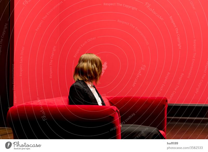 die junge Frau auf dem roten Sofa wendet sich ab - das Rot um sie rum ist ganz schön rot ... roter Raum Junge Frau Blick in die Kamera Drehung Schwung
