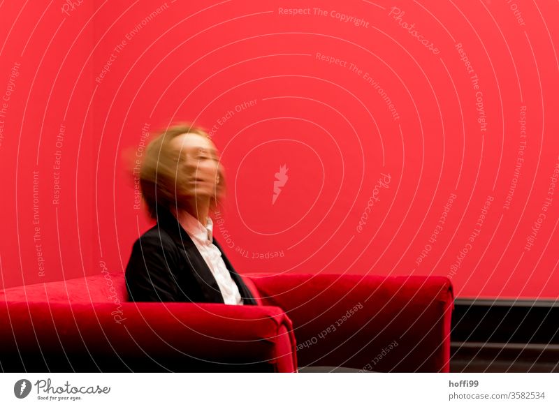 die junge Frau auf dem roten Sofa dreht sich sitzend und blickt in die Kamera - das Rot um sie rum ist ganz schön rot ... roter Raum Junge Frau