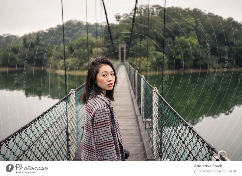Ruhige asiatische Reisende auf Hängebrücke über Fluss stehend Tourist Suspension Brücke Wald Abenteuer Tourismus Urlaub malerisch friedlich Gelassenheit