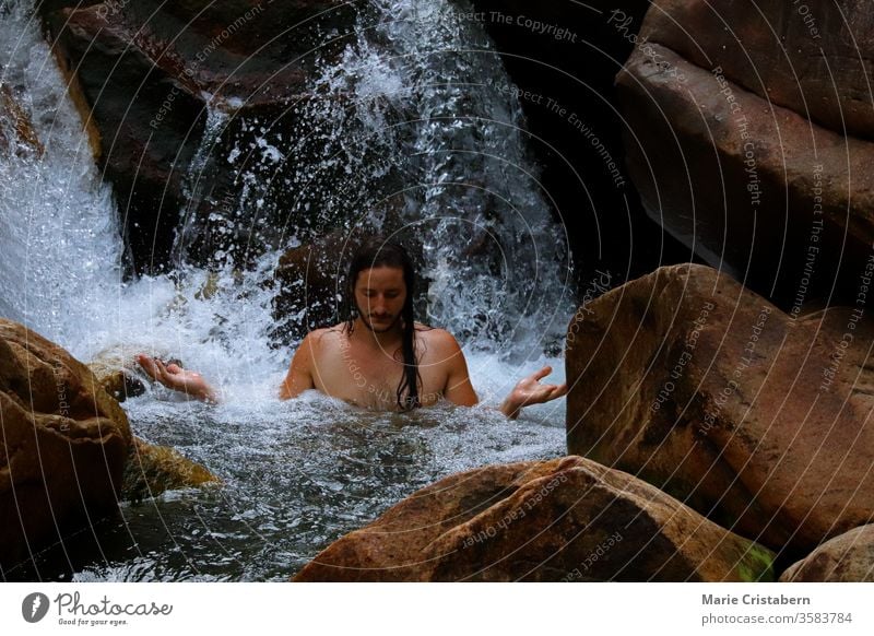 Meditation unter einem kaskadierenden Wasserfall Harmonie mit der Natur neues Zeitalter Wiedergeburt Kraft Kraft des Wassers Kraft der Natur