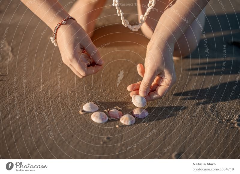 Kleine Mädchenhände, die am Sandstrand des Ozeans ein Herz aus Muscheln formen. Kind Hand Liebe Meeresufer Panzer Sommer Sonne im Freien Natur Lifestyle