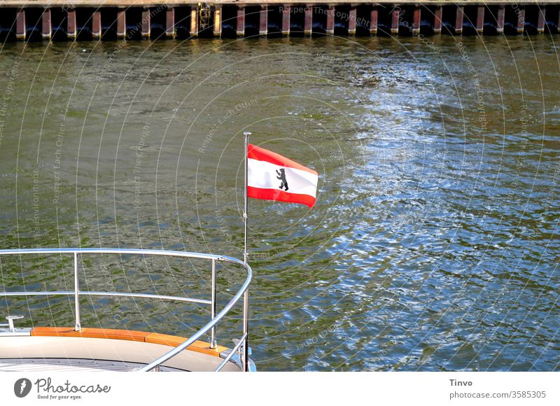 Landesflagge Berliner Bär an der Reling eines Schiffes Flagge Spree Schifffahrt Tourismus Kaimauer Schiffsbug Wappentier weiß rot gestreift Textfreiraum Wasser
