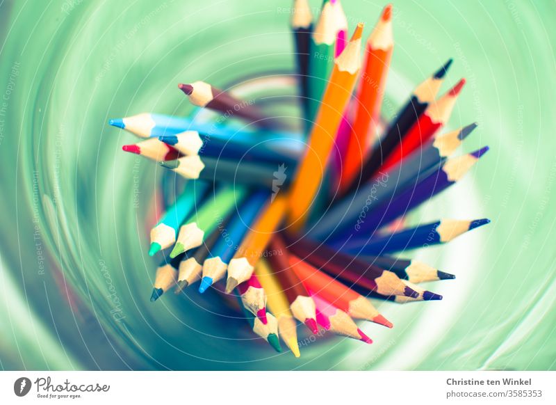 kunterbunte Buntstifte von oben gesehen in einem grünen Wirbel bunt gemischt Stifte Spitzen malen zeichnen Kindergarten Grundschule Schule Farbstift