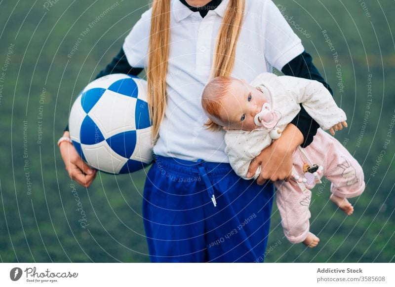 Erntedankfestes Mädchen mit Fussball und Puppe auf dem Feld Fußball Wahl Kind Stereotyp Sport Ball Konzept Uniform Spiel Spielzeug Training Gerät Trikot Spieler