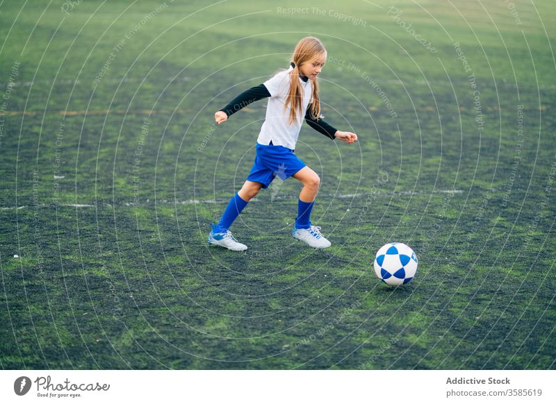 Fokussierte junge Spielerin, die im Sportstadion Fussball spielt Mädchen Fußball Ball Feld Kind laufen spielen Uniform Club Training Aktivität Stadion Athlet