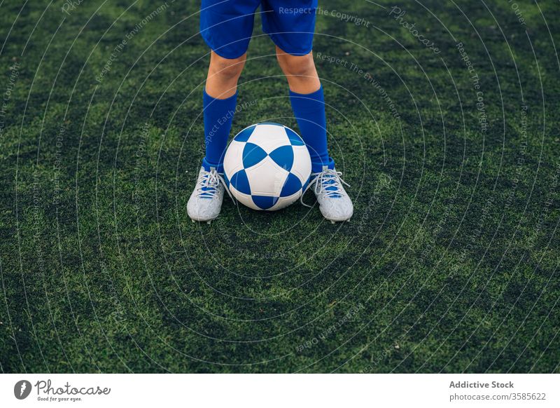 Kornkind in blauer Uniform mit Fussball auf grünem Feld im zeitgenössischen Sportverein Kind Ball Fußball Spieler Bein Klampen Club Gericht Stadion Training