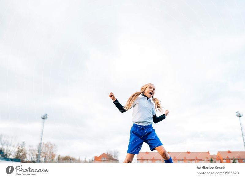 Fröhliche junge Spielerin freut sich über den Erfolg beim Fussballspielen im Sportstadion Mädchen Fußball gewinnen Kind Ball feiern Tor Sieg Glück Feld Triumph