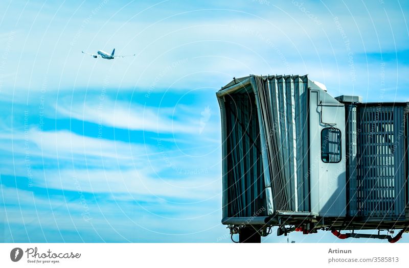 Jet-Brücke nach dem Start der Verkehrsfluggesellschaft auf dem Flughafen und dem Flugzeug, das im blauen Himmel und in weißen Wolken fliegt. Flugzeug-Fluggastbrücke angedockt. Abflug der internationalen Fluggesellschaft.