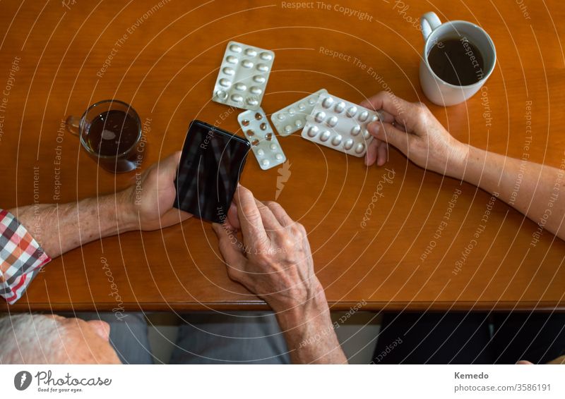 Top-Ansichten von älteren Menschen, die Mobiltelefone benutzen, um zu Hause bei heißen Getränken medizinische Fragen zu beantworten. Ältere Menschen und die Nutzung von Technologie aus medizinischen Gründen.