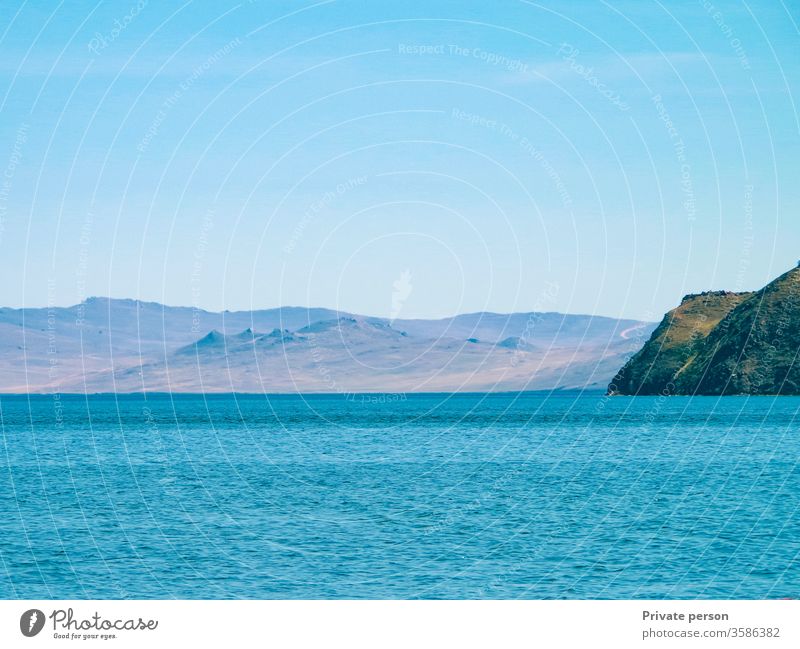 Blaues Meer, wolkenloser Himmel und Berge an einem sonnigen Sommertag. Der Baikalsee ist der tiefste See der Erde, das größte natürliche Süßwasserreservoir