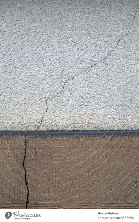 Rissgenau: durchgehender Riss im Mauerwerk Wand Farbfoto Architektur Sockel Beton schadhaft wackelig kaputt Einsturzgefahr instabil Menschenleer