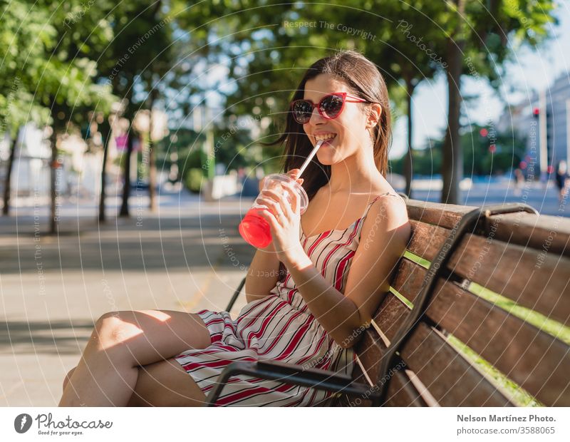Süße Frau auf der Straße. Sie trinkt im Sommer einen kalten Tee. Sie trägt eine Sonnenbrille. im Freien Mädchen Menschen jung trinken Wellness aktiv blau