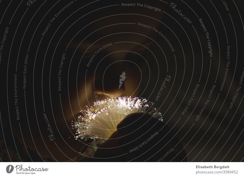kleines Mädchen "riecht" an einem "Strauß" von Lichterketten Kind mädchen geheimnisvoll riechen licht lichter dunkel