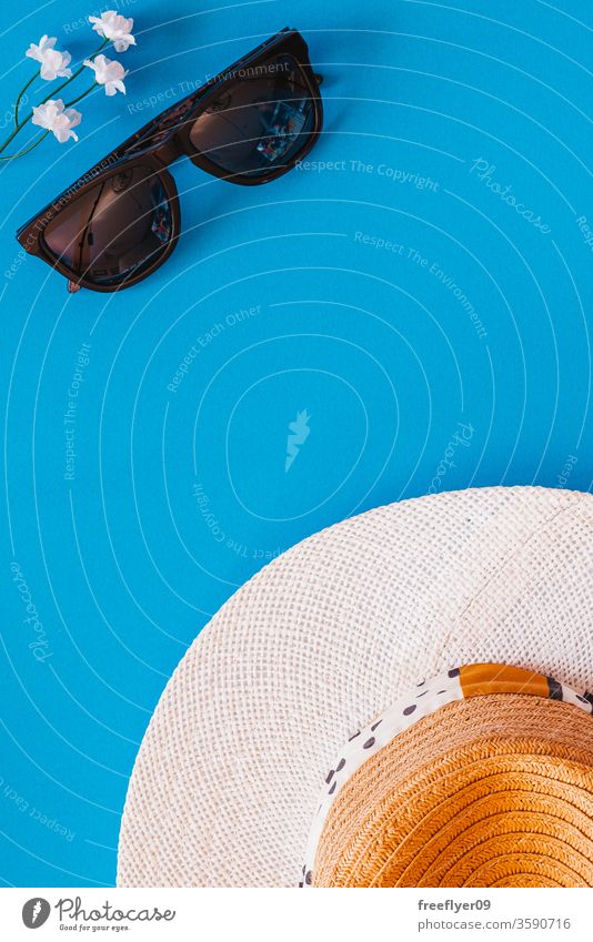 Flächige Darstellung von Objekten im Zusammenhang mit Sommer und Frühling vor blauem Hintergrund Sonnenbrille Hut flache Verlegung Flachlegung Textfreiraum