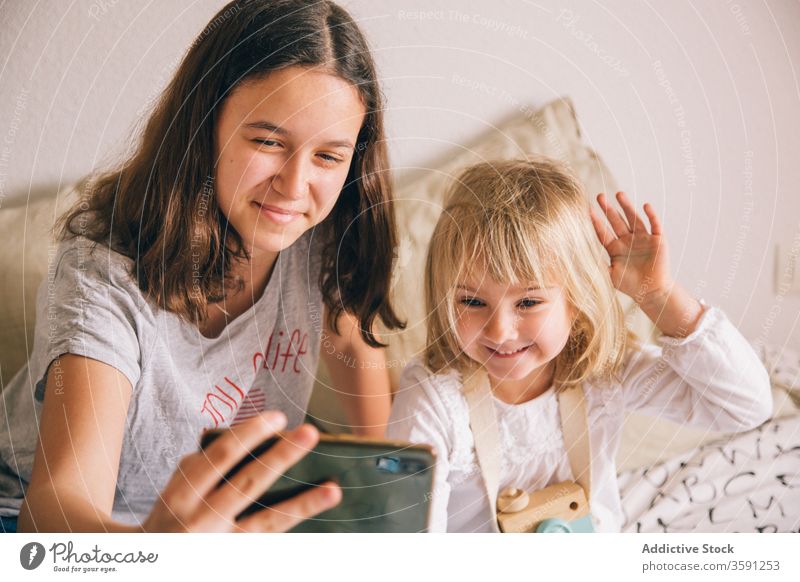 Fröhliche Schwestern, die sich zu Hause am Smartphone vergnügen Selfie Grimasse Mädchen Geschwisterkind benutzend Spaß haben gestikulieren Teenager wenig