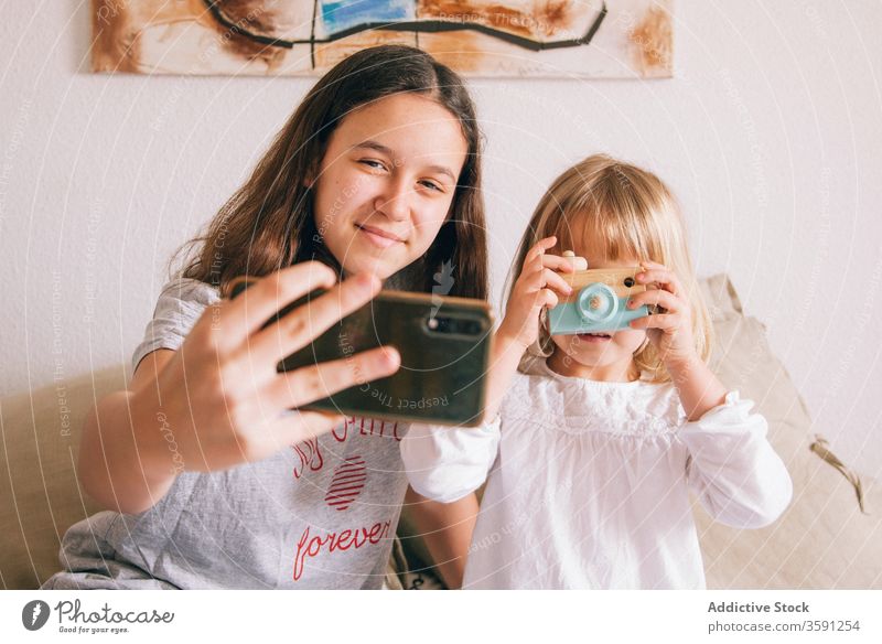 Zufriedene Schwestern nehmen Selbstliebe am Mobiltelefon Selfie Smartphone Teenager wenig Mädchen benutzend charmant Inhalt Spaß haben Spielzeug Fotokamera