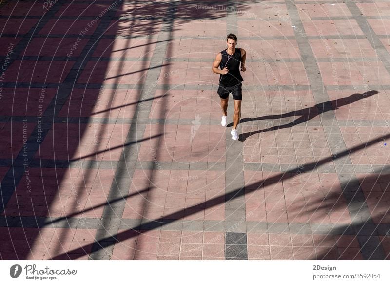 Draufsicht auf einen Athleten, der in schwarzer Sportkleidung auf der Straße trainiert. Mann Erwachsener Joggen Lifestyle sportlich Läufer Übung jung aktiv