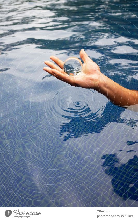 Menschliche Hand hält eine Glaskugel über das Wasser durchsichtig Kristallkugel Ball Reflexion & Spiegelung Brille Licht Urlaub mittelgroß Zauberei u. Magie