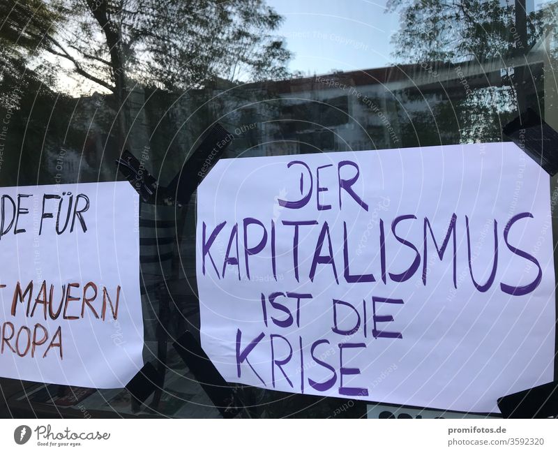 Schaufensteraushang: "Der Kapitalismus ist die Krise". Foto: Alexander Hauk Neoliberalismus Protest Demokratie Meinungsfreiheit Spiegelung Tageslicht