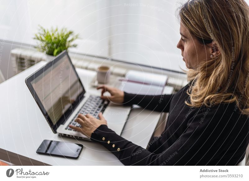Junge Frau, die zu Hause mit dem Laptop arbeitet Arbeit heimwärts online abgelegen Tisch lässig beschäftigt jung Arbeitsplatz freiberuflich Gerät Apparatur