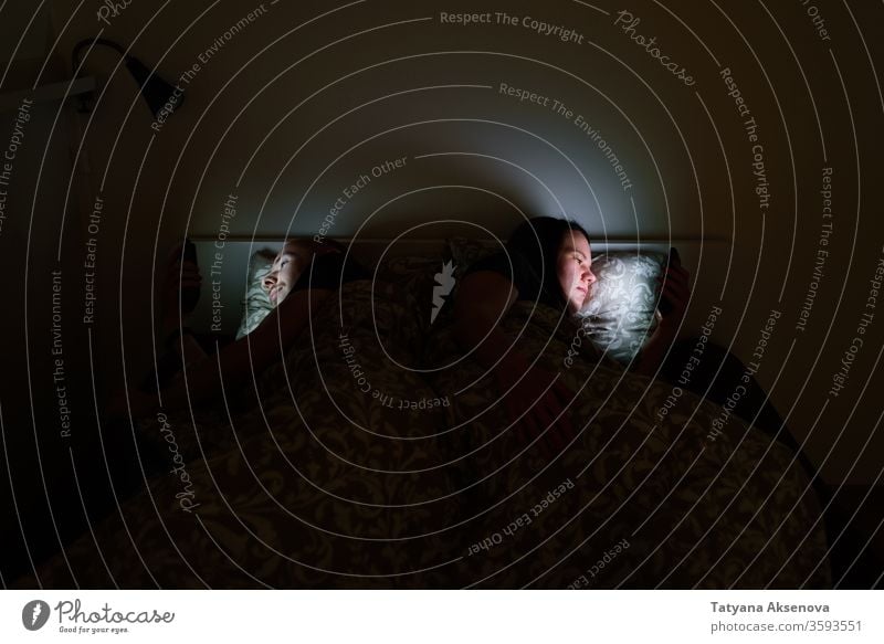 Ehepaar benutzt Telefone, die vor dem Schlafengehen im Bett liegen online Paar Schlafstörung schlafen benutzend Sucht Internet Problematik Texten Surfen