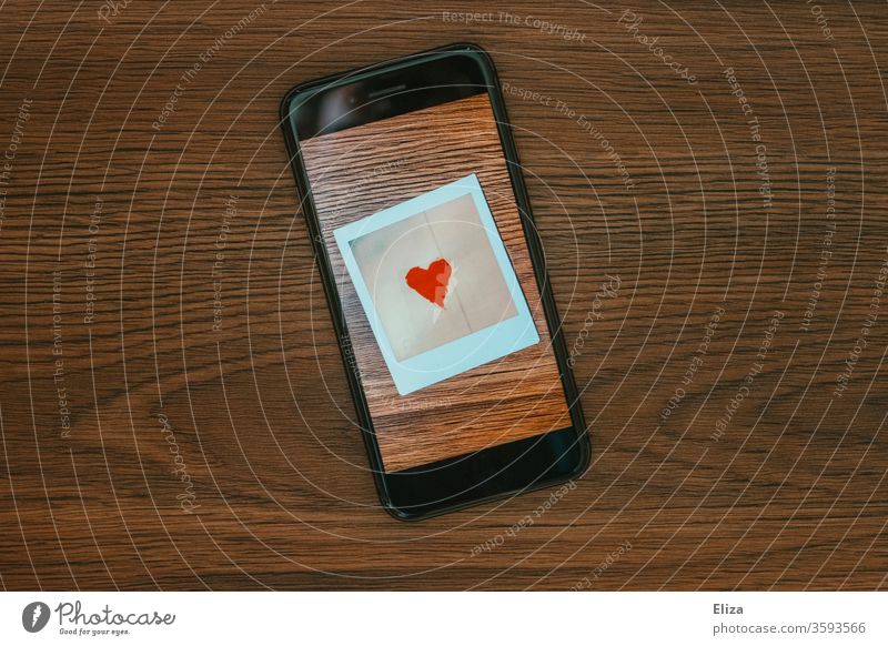 Ein Foto mit einem Herz auf dem Bildschirm eines Smartphones. Online Dating. Tinder. Kommunikation. Liebe Display Polaroid Symbol Gefühle Emotionen chatten