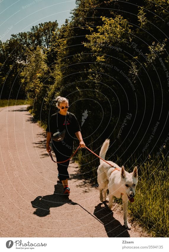 Junge Frau geht mit weißem Schäferhund gassi gassi gehen cool lässig fashion mode jung jugendlich schäferhund schön spazieren natur landschaft sommer sonne