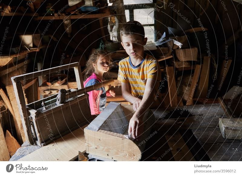 Ein Junge baut in der Schreinerei ein Vogelhäuschen aus Holz. Die neugierige kleine Schwester versucht zu sehen, was er hinter seinem Rücken macht. Heimwerker