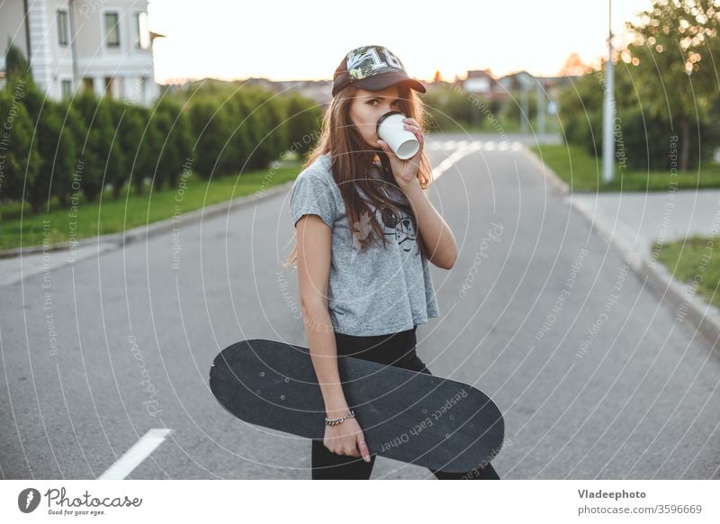 Das Mädchen mit einem aktiven Lebensstil beginnt mit Morgenkaffee und Schlittschuhlaufen. Tasse Kaffee trinken Frau Straße Stil Mode jung lässig schön im Freien