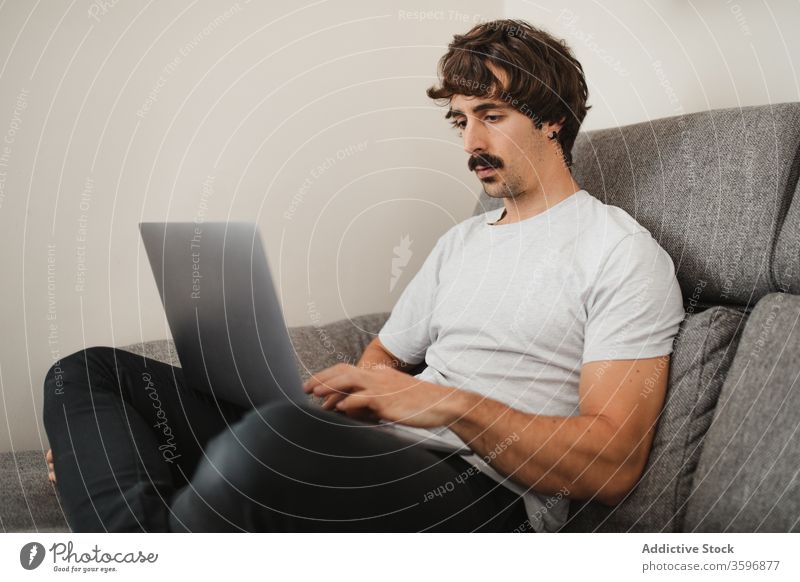 Gutaussehender männlicher Freiberufler mit Laptop im Wohnzimmer Unternehmer abgelegen Projekt Mann freiberuflich Arbeit benutzend online Konzentration heimwärts