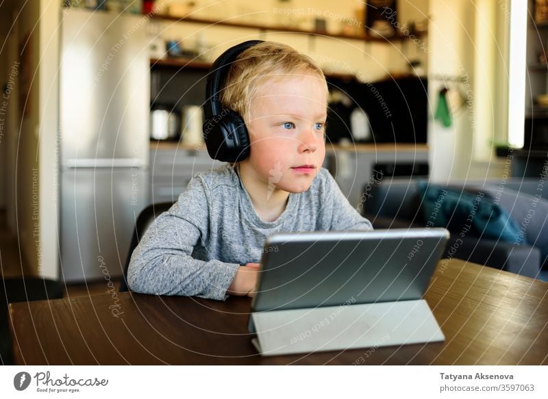Kleiner Junge lernt zu Hause. Webinar auf einem mobilen Tablet ansehen. Bildung Homeschooling Kind online Lernen E-Learning heimwärts Entfernung zuschauend