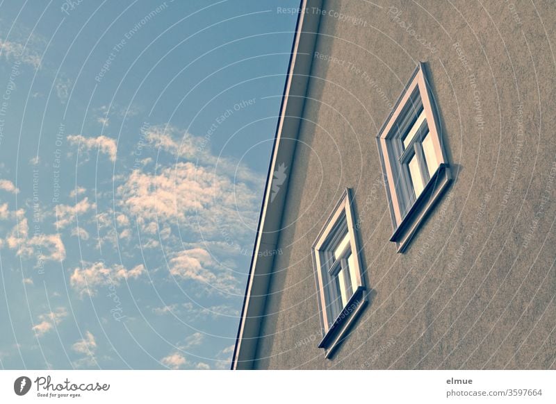 Teilansicht einer Hausfassade mit Dachrand und zwei Fenstern sowie Schönwetterwolken am Himmel Wolkenhimmel Spiegelung Holzfenster Froschperspektive Hälfte