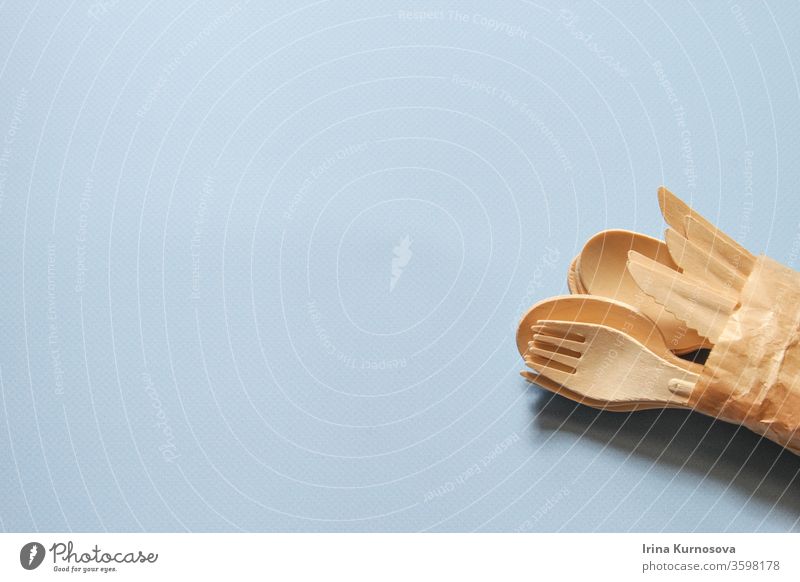 Löffel, Gabeln, Messer aus Holz auf dem blauen Hintergrund. Umweltfreundliche Einweg-Küchenutensilien aus Holz. Ökologie, Null-Abfall-Konzept. Flachlegen. Ansicht von oben