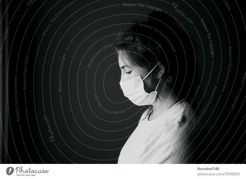 Junge Frau trägt Schutzmaske gegen Covid-19, Coronavirus sieht depressiv und isoliert aus, Schwarz-Weiß-Portrait-Virus-Konzept Hintergrund medizinisch Business