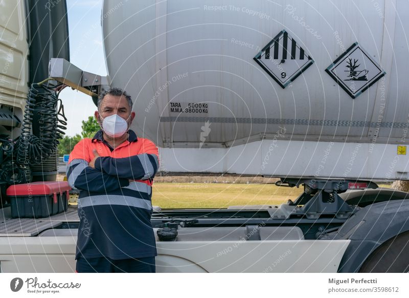 Lkw-Fahrer mit Gesichtsmaske posiert neben einem Gefahrgut-Tankwagen gefährliche Güter Mann hohe Sichtbarkeit adr Kabine Brennstoff Flüssigtransport Veteran