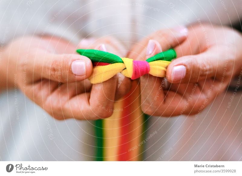 Hände halten regenbogenfarbene Bänder zur Feier des Tags des Stolzes, der Zerstreuung, der Gleichberechtigung und der LGBTQ-Gemeinschaft Tag des Stolzes